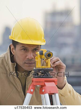 African male surveyor looking through measuring device View Large Photo Image Stock Image - African male surveyor looking through measuring device. Fotosearch