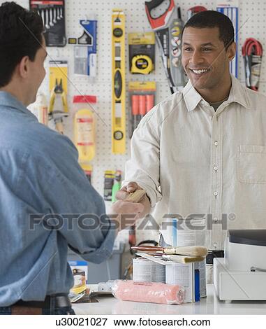 African sales clerk at hardware store handing over credit card View Large Photo Image Stock Photo - African sales clerk at hardware store handing over credit card. Fotosearch