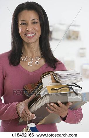 African woman holding pile of textile swatches View Large Photo Image Stock Photograph - African woman holding pile of textile swatches. Fotosearch