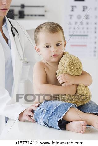 Baby hugging teddy bear at doctor View Large Photo Image Stock Image - Baby hugging teddy bear at doctor. Fotosearch