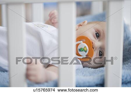 Picture - Baby in crib with pacifier. Fotosearch