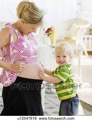 Stock Photo - Baby touching mother’s pregnant belly. Fotosearch