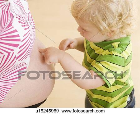 Baby touching mother’s pregnant belly View Large Photo Image Stock Photo - Baby touching mother’s pregnant belly. Fotosearch