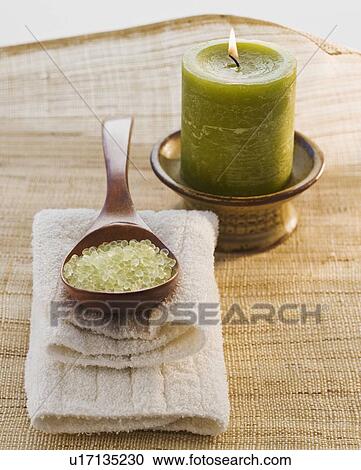 Stock Image - Bath salt in spoon next to candle. Fotosearch