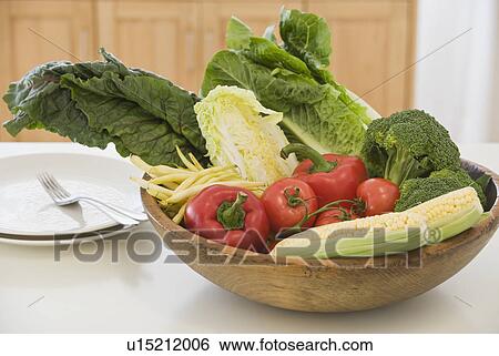 Stock Photograph - Bowl of vegetables next to dishes. Fotosearch