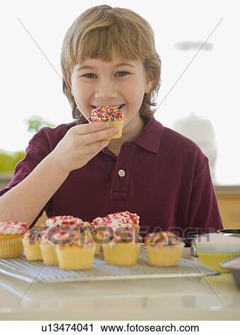Boy eating home-made cupcake View Large Photo Image Stock Image - Boy eating home-made cupcake. Fotosearch