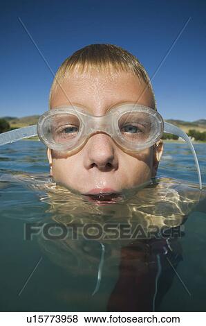 Stock Photo - Boy wearing swimming goggles in water, Utah, United States. Fotosearch