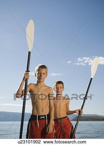 Stock Image - Brothers holding canoe paddles, Utah, United States. Fotosearch