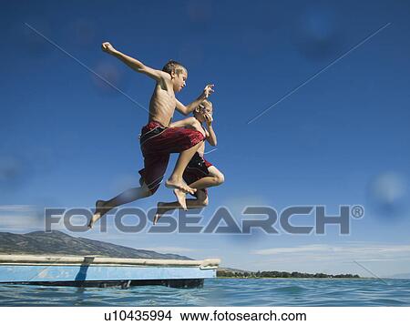 Brothers jumping off dock into lake, Utah, United States View Large Photo Image Picture - Brothers jumping off dock into lake, Utah, United States. Fotosearch