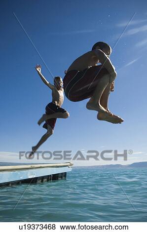 Brothers jumping off dock into lake, Utah, United States View Large Photo Image Stock Photo - Brothers jumping off dock into lake, Utah, United States. Fotosearch