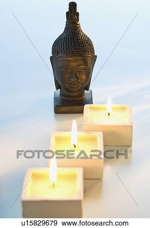 Buddha statue next to lit candles View Large Photo Image Stock Photo - Buddha statue next to lit candles. Fotosearch