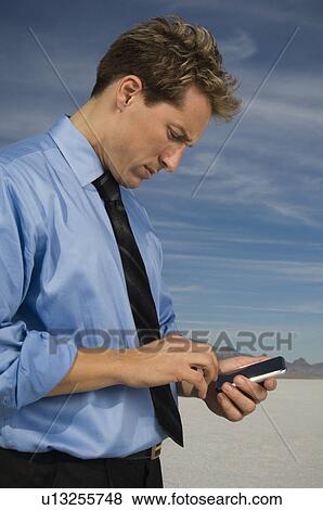 Businessman dialing cell phone, Salt Flats, Utah, United States View Large Photo Image Stock Photo - Businessman dialing cell phone, Salt Flats, Utah, United States. Fotosearch