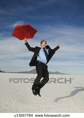 Picture - Businessman holding umbrella and jumping, Salt Flats, Utah, United States. Fotosearch
