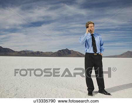 Stock Image - Businessman talking on cell phone, Salt Flats, Utah, United States. Fotosearch