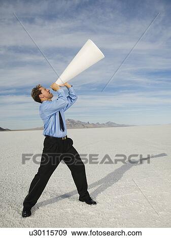 Stock Photo - Businessman yelling into megaphone, Salt Flats, Utah, United States. Fotosearch