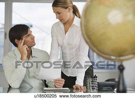 Stock Photography - Businesspeople discussing paperwork. Fotosearch