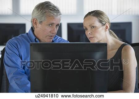 Stock Image - Businesspeople looking at laptop. Fotosearch