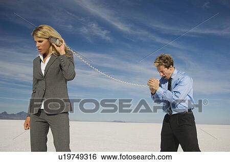 Stock Photograph - Businesspeople talking with can and string phone, Salt Flats, Utah, United States. Fotosearch