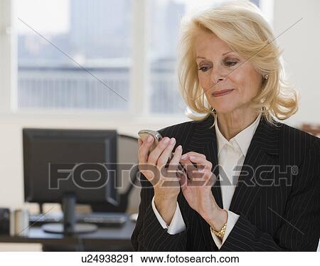 Stock Image - Businesswoman dialing cell phone. Fotosearch