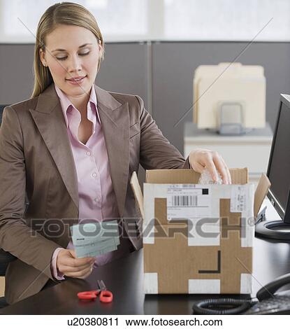 Stock Image - Businesswoman opening package. Fotosearch