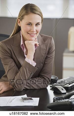 Businesswoman sitting at desk View Large Photo Image Stock Image - Businesswoman sitting at desk. Fotosearch