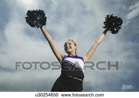 Cheerleader holding pom poms over head View Large Photo Image Stock Image - Cheerleader holding pom poms over head. Fotosearch