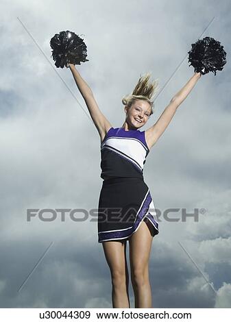 Stock Photo - Cheerleader with pom poms jumping. Fotosearch