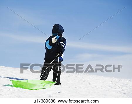 Stock Photo - Child pulling sled in snow. Fotosearch