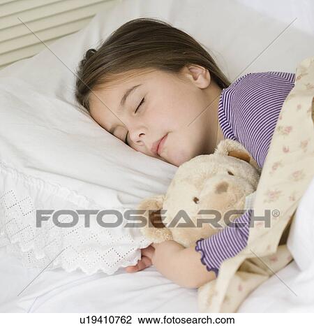 Stock Image - Close up of girl sleeping with teddy bear. Fotosearch