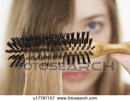 Stock Photo - Close up of hairbrush in woman’s hair. Fotosearch