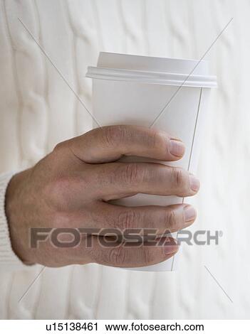 Stock Image - Close up of man holding take out coffee. Fotosearch