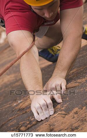 Stock Image - Close up of man rock climbing. Fotosearch