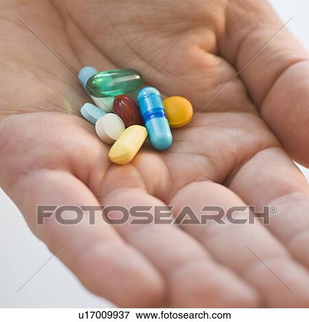 Stock Photo - Close up of medication in man’s hand. Fotosearch