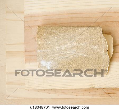 Stock Image - Close up of sandpaper on wood. Fotosearch