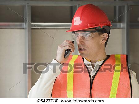 Stock Image - Construction worker talking into cell phone. Fotosearch