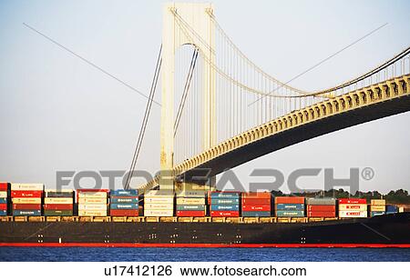 Stock Photograph - Container barge under Verrazano Narrows Bridge, New York City. Fotosearch