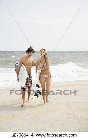 Couple carrying surfboards at beach View Large Photo Image Picture - Couple carrying surfboards at beach. Fotosearch