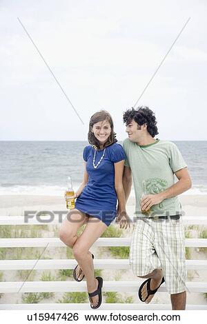 Stock Photograph - Couple drinking beer at beach. Fotosearch