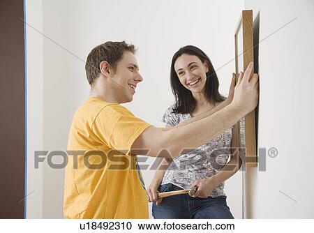 Stock Image - Couple hanging picture. Fotosearch