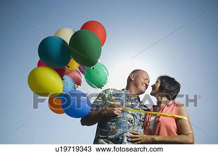 Stock Image - Couple holding balloons. Fotosearch
