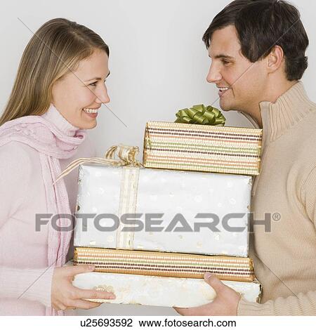 Stock Image - Couple holding pile of gifts. Fotosearch
