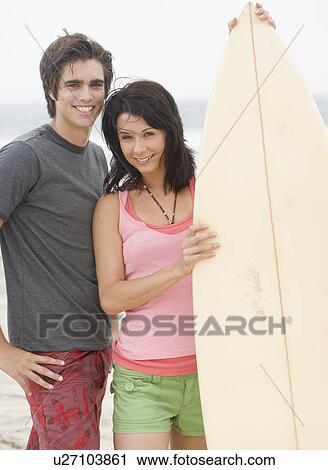 Couple holding surfboard and smiling View Large Photo Image Stock Image - Couple holding surfboard and smiling. Fotosearch