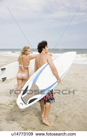Couple holding surfboards at beach View Large Photo Image Stock Photo - Couple holding surfboards at beach. Fotosearch