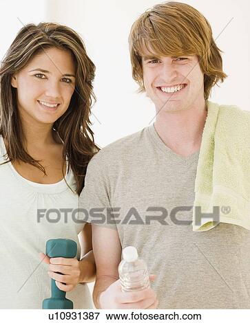 Stock Photo - Couple holding water bottle and weight. Fotosearch