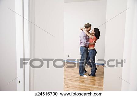 Stock Image - Couple hugging in empty new house. Fotosearch