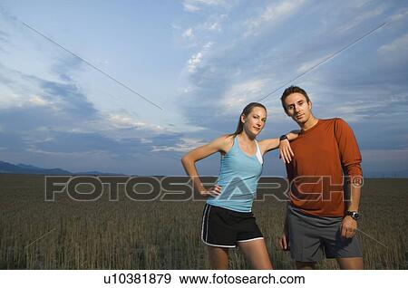 Stock Photo - Couple in athletic gear next to field. Fotosearch