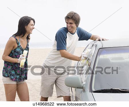 Couple laughing next to car at beach View Large Photo Image Stock Image - Couple laughing next to car at beach. Fotosearch