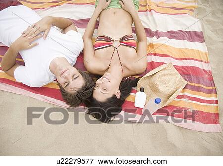 Stock Photo - Couple laying on blanket at beach. Fotosearch