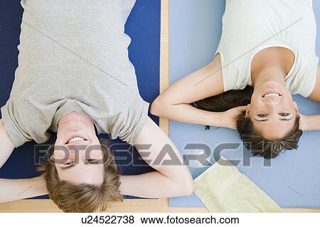 Stock Photo - Couple laying on yoga mats. Fotosearch