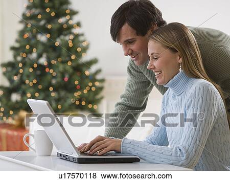 Couple looking at laptop View Large Photo Image Stock Photo - Couple looking at laptop. Fotosearch